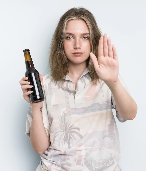 Woman makes a stop gesture with her hand while holding a beer bottle