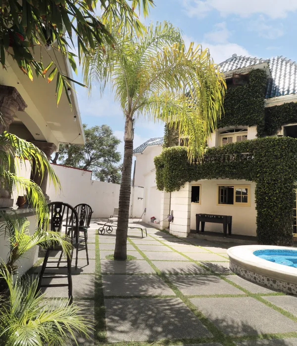 An outdoor courtyard with a palm tree, a small pool, and ivy-covered walls featuring a foosball table and seating.